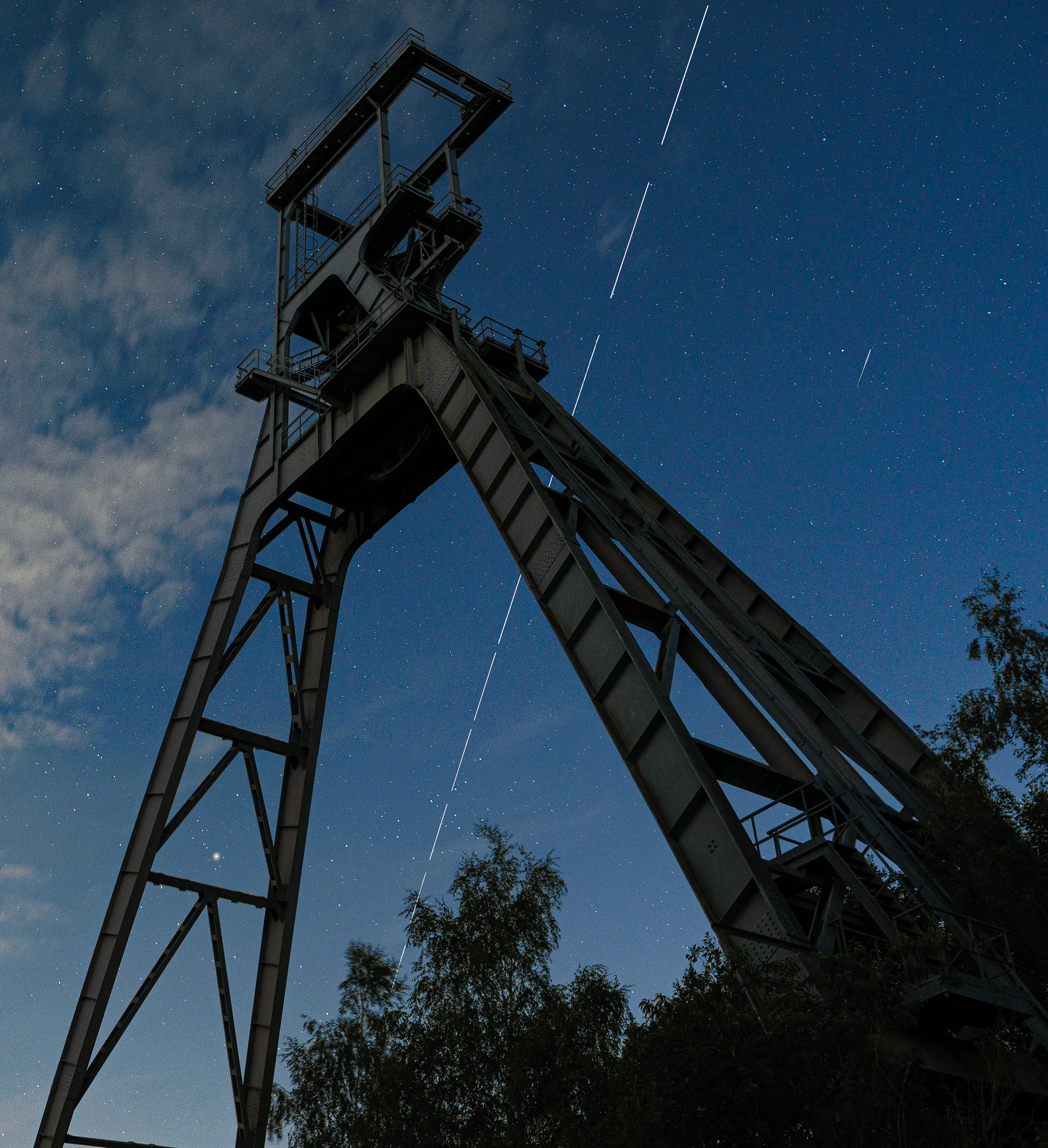 The headframe of a disused mine silhouetted against a deep blue night sky