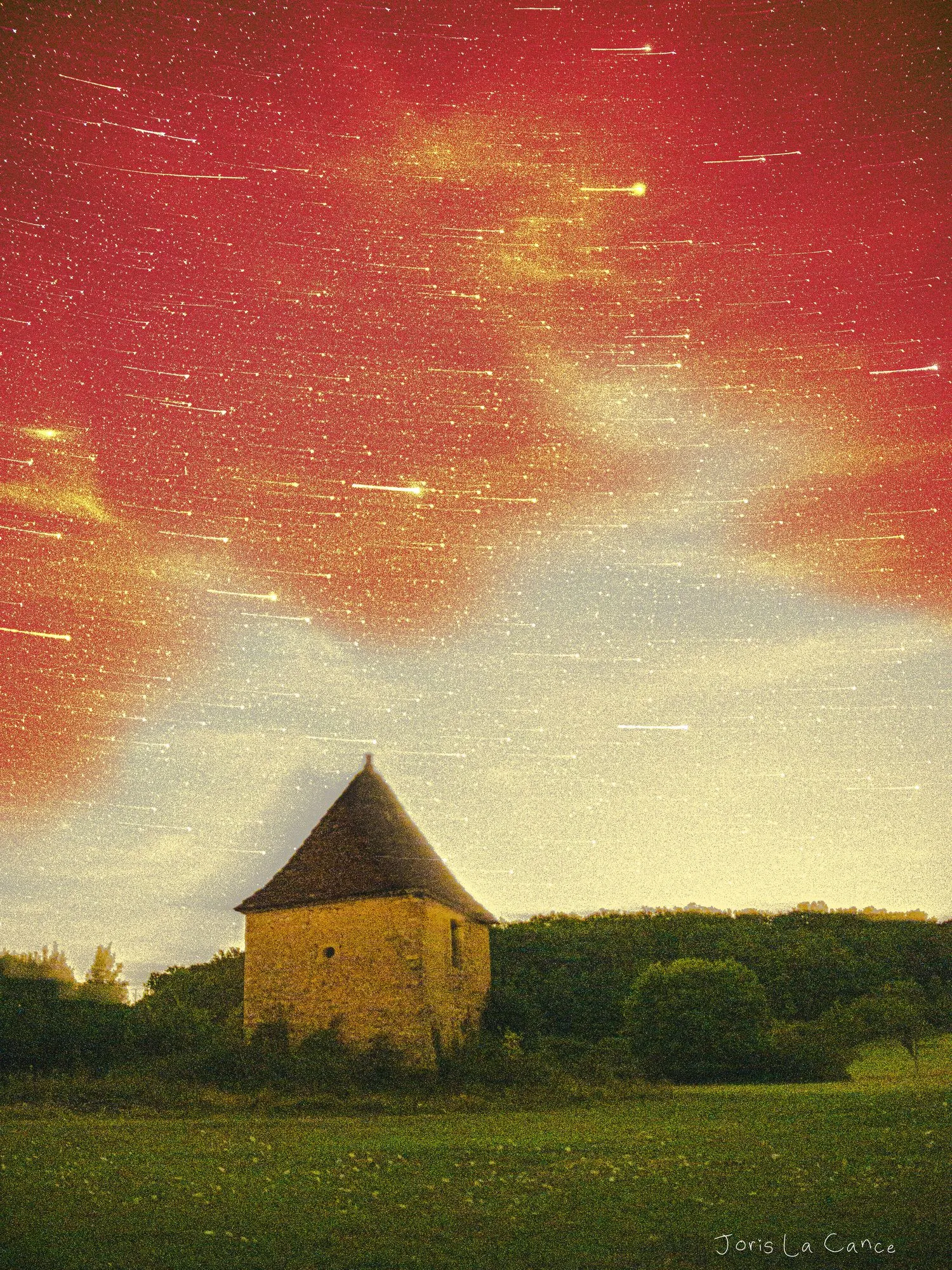 A stone pigeonnier with a conical tiled roof standing in a meadow, short star trails streaking a crimson sky above