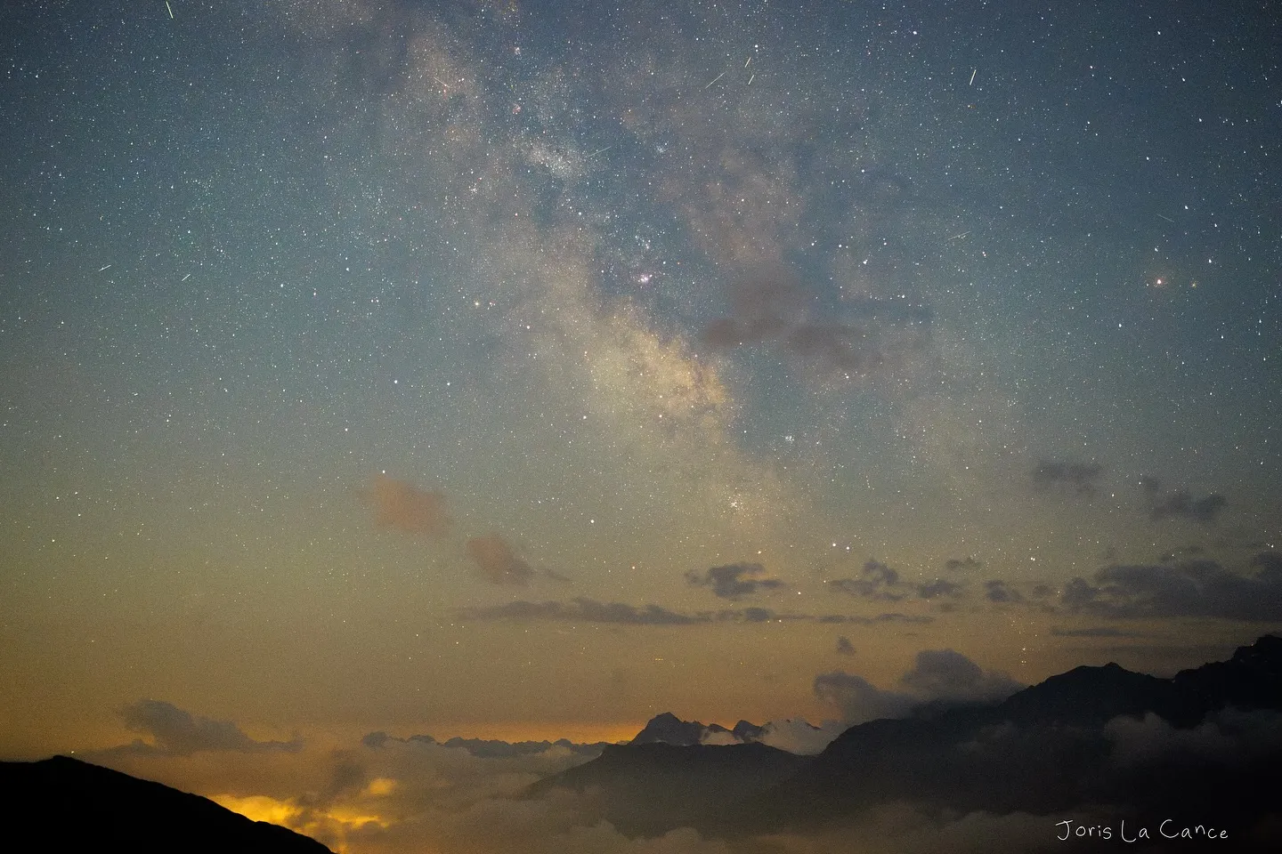 The Milky Way core rising above a sea of cloud, mountain ridges below